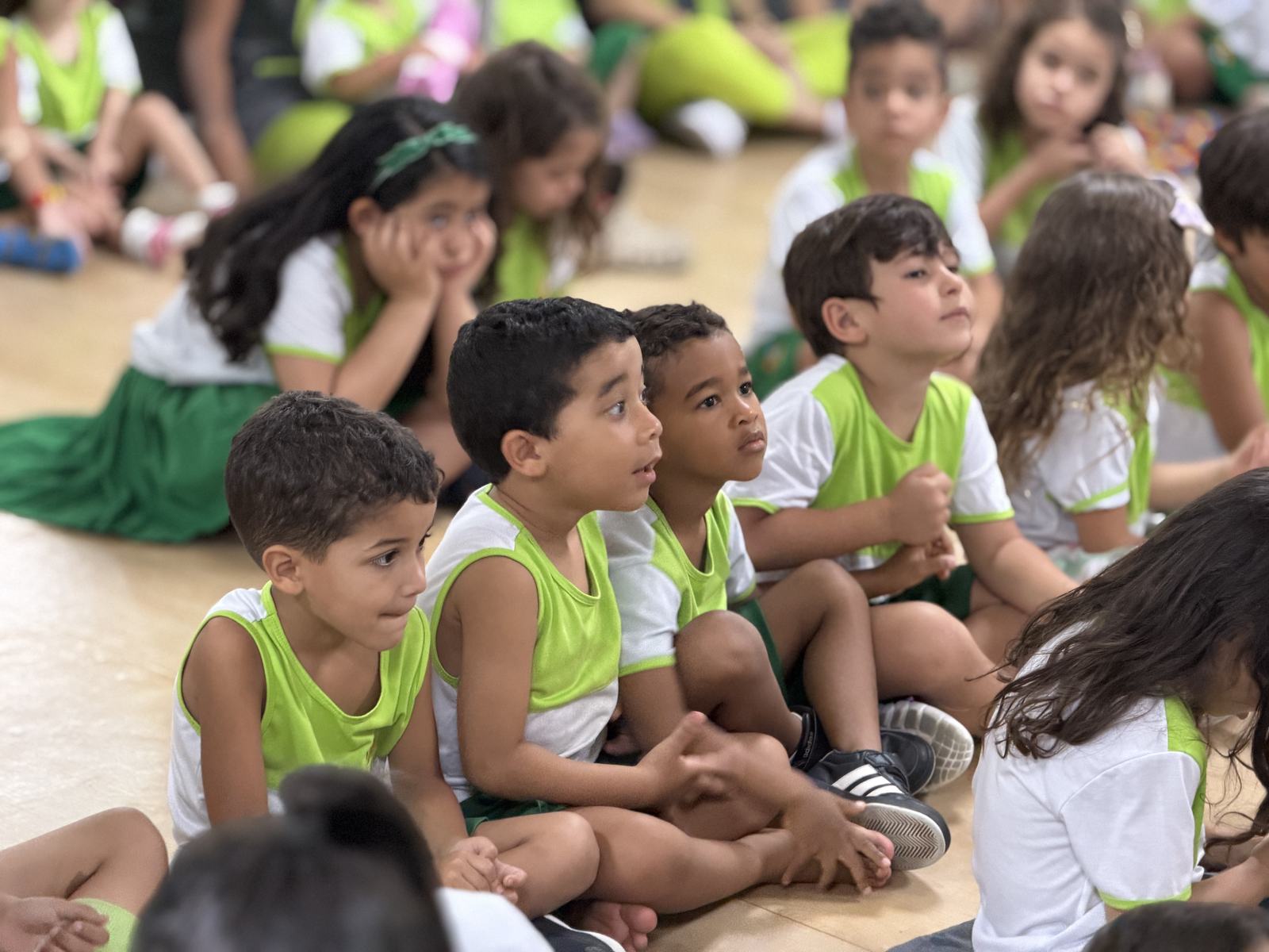 Crianças sentadas no chão, atentas a uma atividade em sala